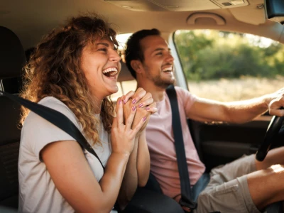 Man and woman smiling in a car as they drive