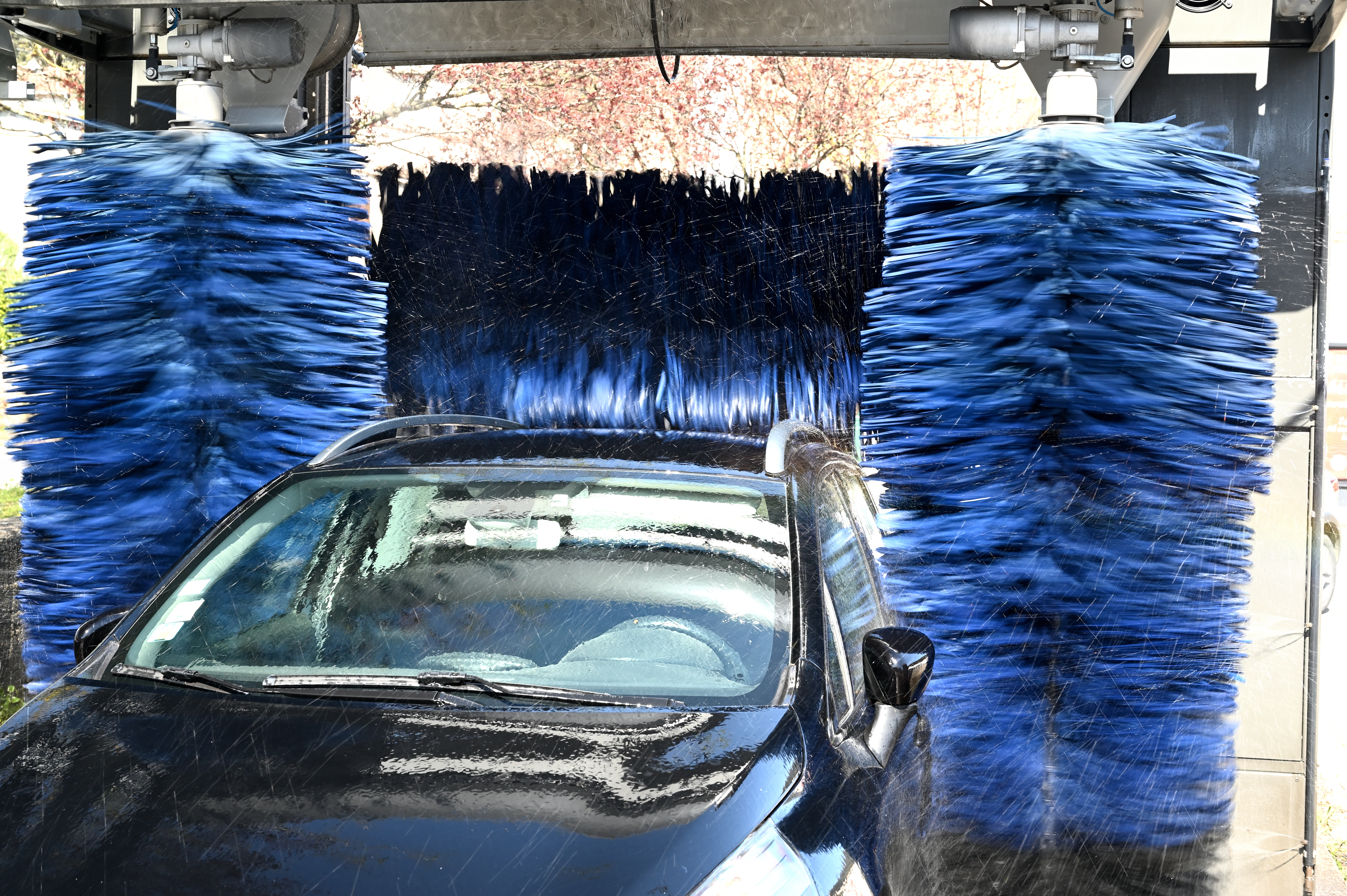 Car being cleaned by automatic blue car wash brushes
