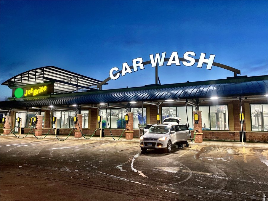 Exterior shot of Jet Brite Express Car Wash tunnel with car in front using the free vacuums